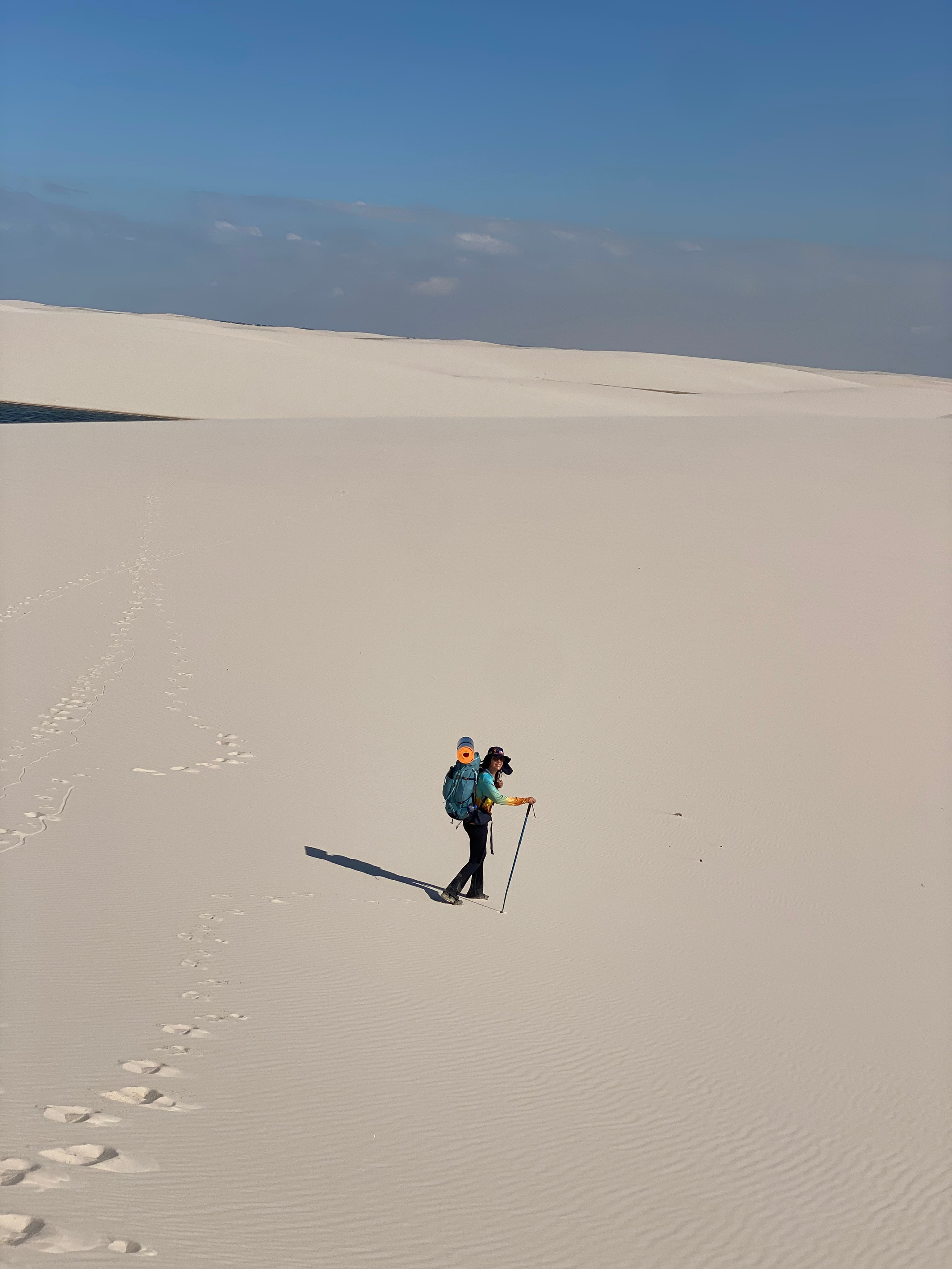 Caminhante com mochila atravessando uma duna